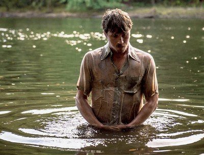 Costume design by Anette Cseri for the film Burden: a man standing waist deep in a river in a soaked work shirt
